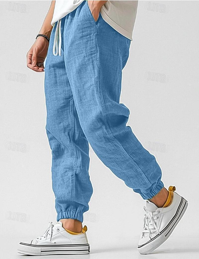 Blue jogger pants worn with white sneakers on a light gray background