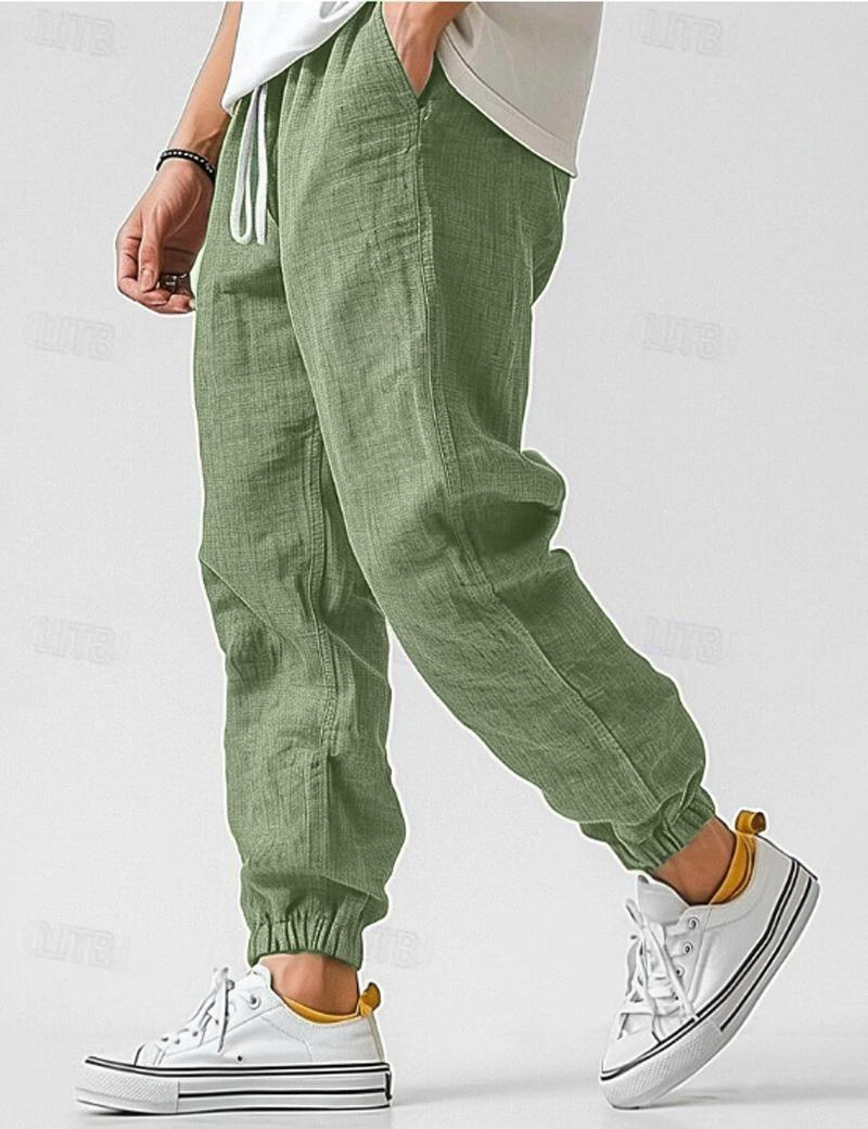Green jogger pants worn with white sneakers on a plain background