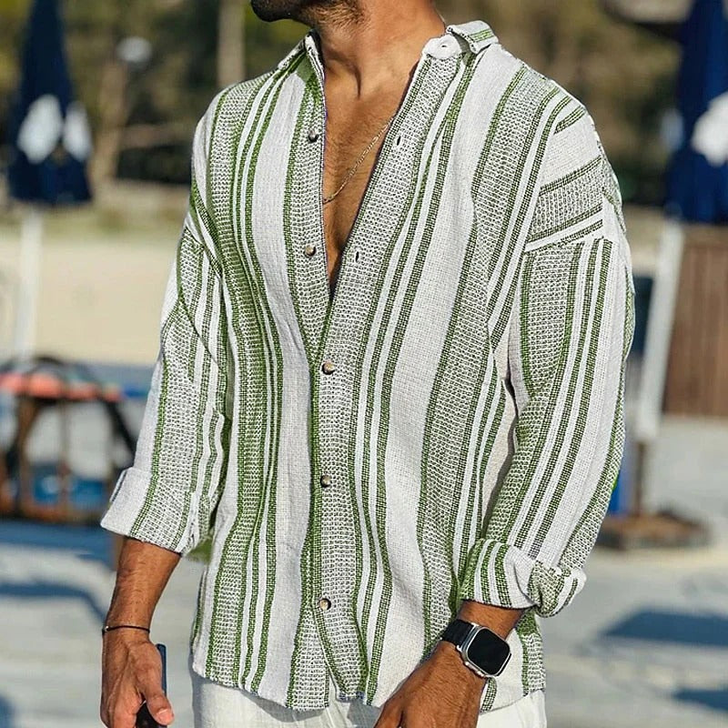 Man wearing a green and white striped shirt with a blurred beach background
