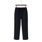 Linen black pants on a hanger against a white background
