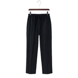 Linen black pants on a hanger against a white background