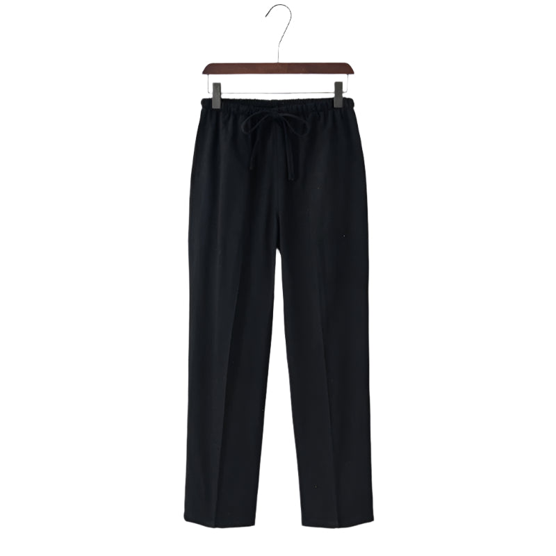 Linen black pants on a hanger against a white background