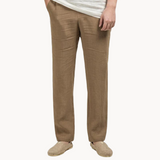 Person wearing beige linen pants on a white background
