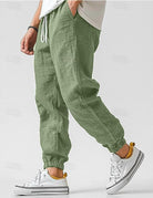 Green jogger pants worn with white sneakers on a plain background