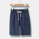 Blue linen shorts with a drawstring on a hanger against a white background