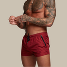 Person wearing red swim shorts with a neutral background