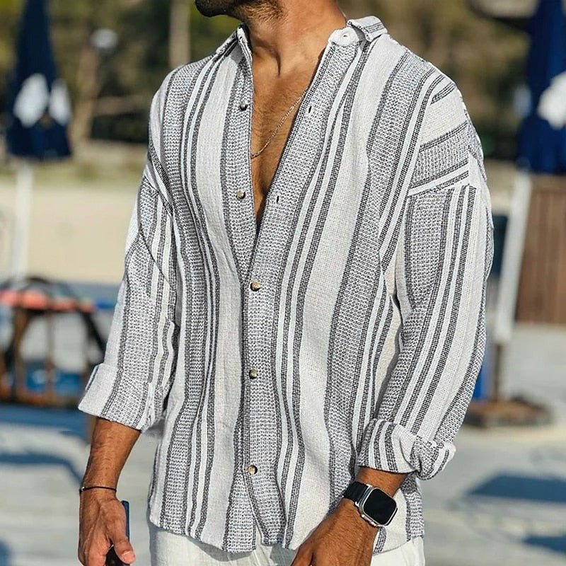 Man wearing a striped shirt with rolled-up sleeves in an outdoor setting