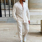 Man wearing a beige linen outfit standing in front of a building.