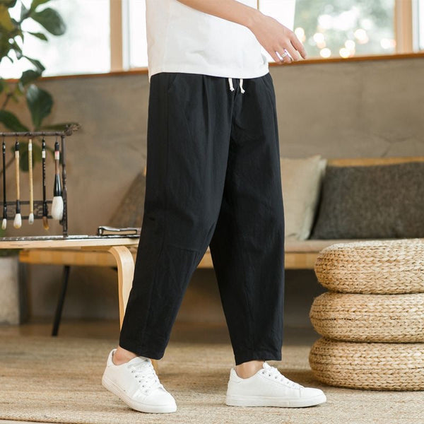 Person wearing black pants and white sneakers in a living room setting