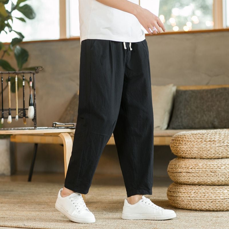 Person wearing black pants and white sneakers in a living room setting
