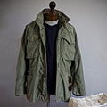 "Men's vintage military jacket with hidden hood, snap-button cargo pockets, wind-resistant, rugged style."